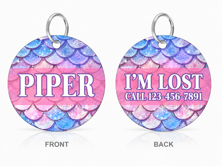 Front and back views of a round pet ID tag with a mermaid scale pattern in pink, purple, and blue. The front side displays the name 'PIPER' in white, and the back side displays 'I'M LOST CALL 123-456-7891' in purple.