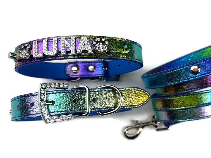 A set of iridescent rainbow leather pet accessories, including two collars and a leash, decorated with rhinestones and the name 'LUNA'.