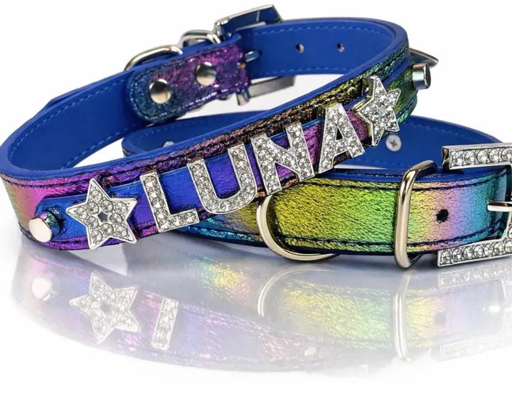 iridescent blue dog collars with silver-tone hardware, one featuring a star and the other 'LUNA' with rhinestone lettering, displayed on a reflective white surface.